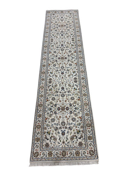A long rectangular area rug with an intricate floral and geometric pattern, featuring a cream-colored center field, blue and brown borders, and fringed ends, shown against a plain white background.