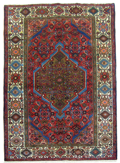 A traditional Persian-style area rug with a complex geometric and floral pattern, featuring a dominant red field, blue accents, and a cream-colored border.